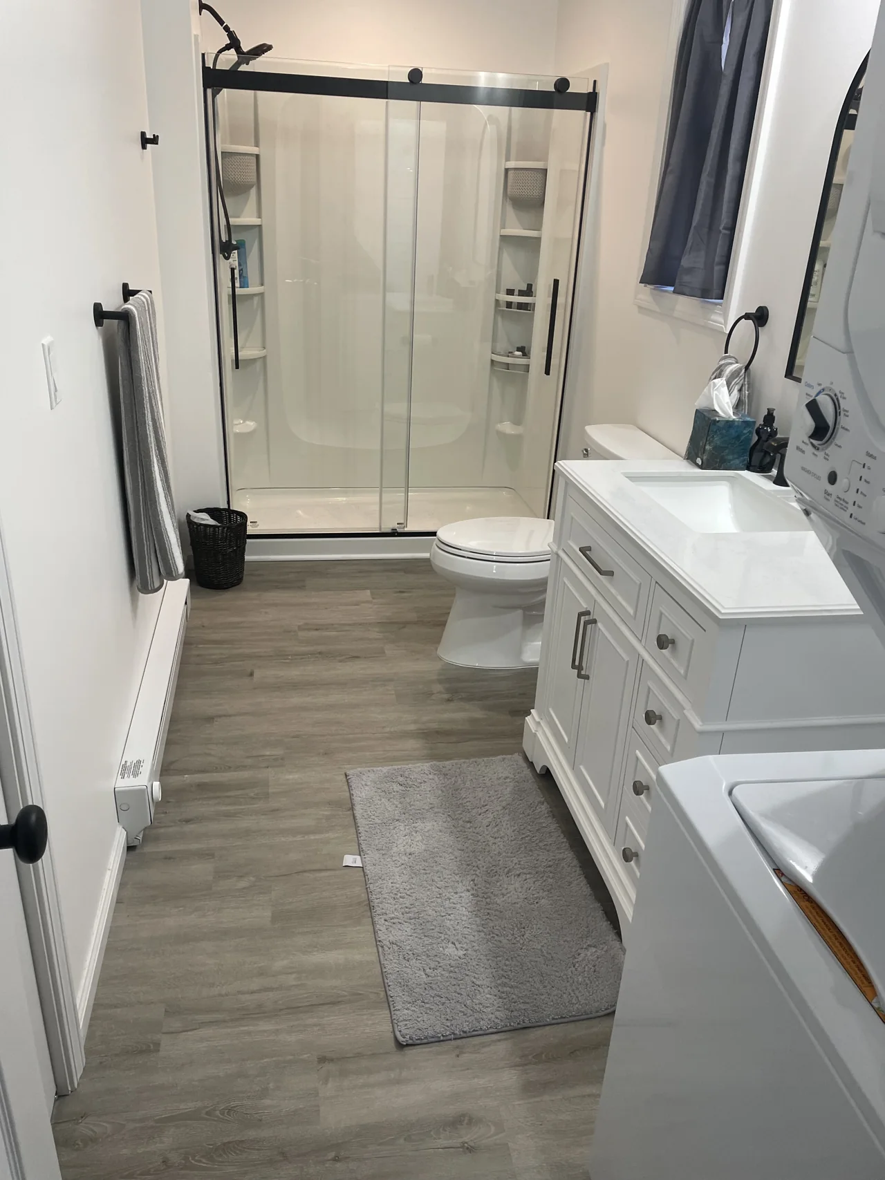 Bathroom with glass shower doors, white vanity and wood-look flooring