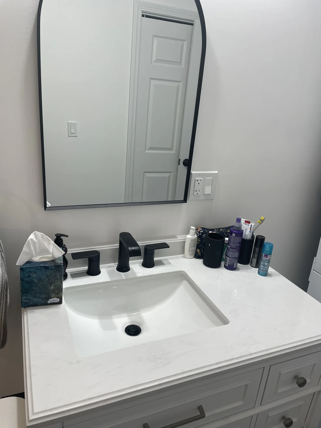 White bathroom vanity with rectangular mirror and dark fixtures
