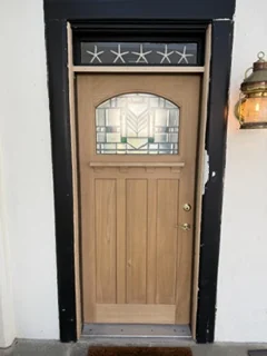 Exterior view of the installed wood door with decorative glass and dark trim