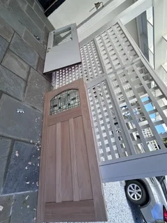 Decorative glass entry door resting on porch rails during the work
